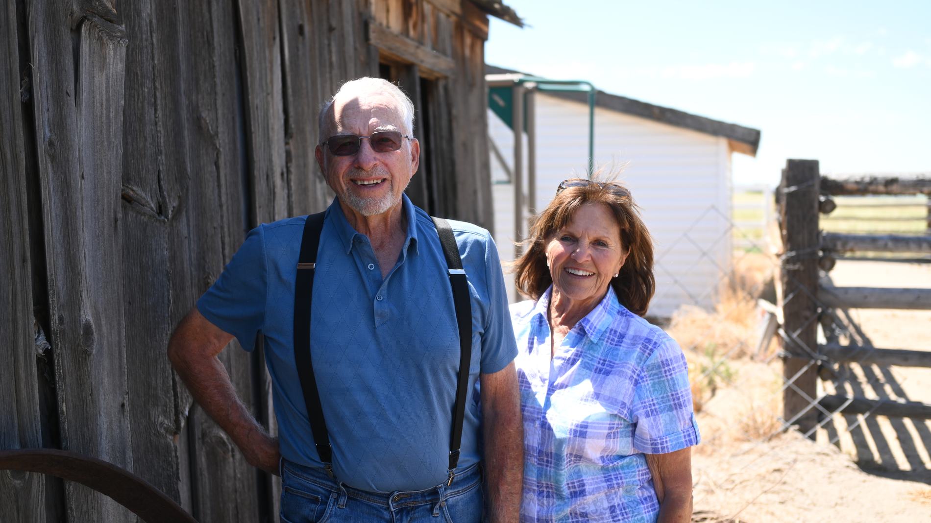Lee and Judy standing together outside a weathered wooden barn